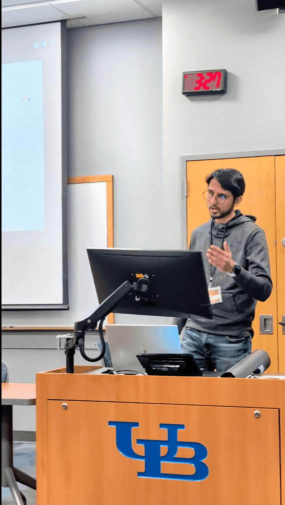 Adnan presenting at a podium in a University at Buffalo lecture hall